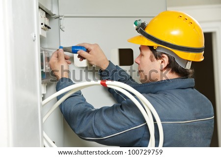 One electrician builder at work installing energy saving meter into electric line distribution fuseboard