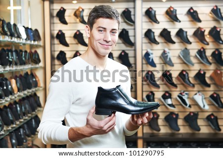 Young man choosing shoes during footwear shopping at shoe shop