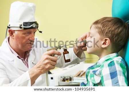 Medical otolaryngologist ear nose throat doctor rinsing nose at boy child