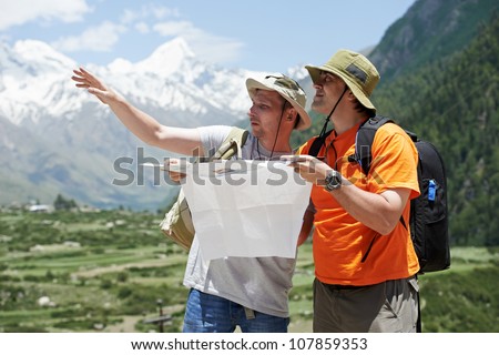 two tjourist trvellers discussing route with map in Himalayas mountains