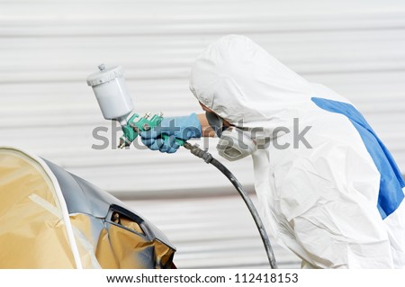 auto mechanic worker painting car bumper at automobile repair and renew service station shop by spraing black color paint