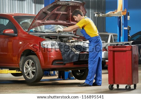 Mechanic tightening a screw using a spanner at an auto repair shop