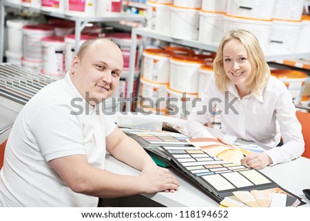 Assistant seller help choosing paint color and demonstrating matching samples to buyer at hardware store