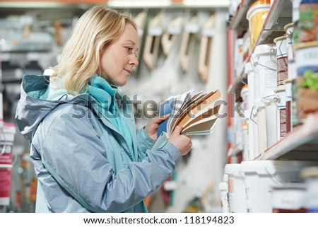 Young woman choosing paint using color samples during hardware shopping in home improvement store supermarket