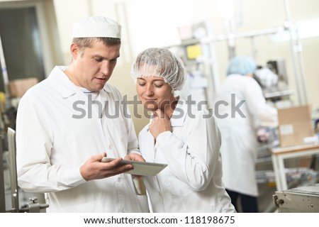 Two pharmaceutical workers discussing manufacture project with tablet computer at pharmacy industry