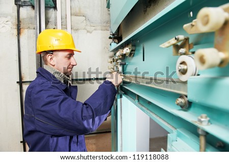 One machinist worker at work adjusting elevator mechanism of lift with spanner