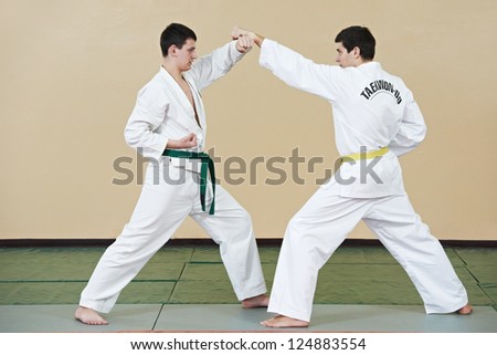 Two young adult people in kimono training taekwondo martial art at gym