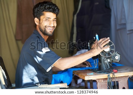 Portrait of indian man tailor at work place with sewing machine
