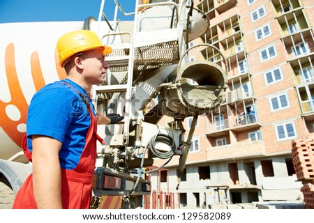 builder worker in uniform in front of concrete mixer truck at construction site