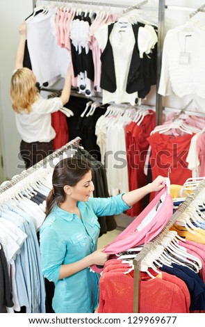Young woman choosing garments during clothing shopping at apparel store