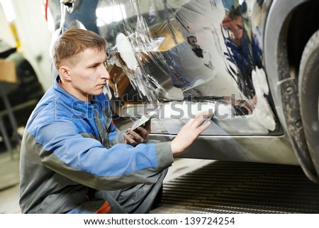 auto repairman worker in automotive industry examining car body painting or repaint at auto repair shop