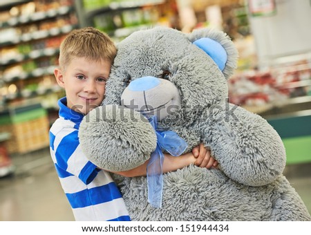 Little child boy with big plush bear gift in toy shop or supermarket store