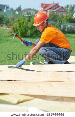 construction carpenter worker nailing wood board with hammer on roof installation work