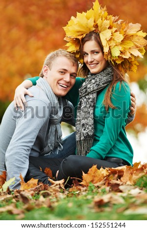 Two young smiling people with autumn maple leaves in park at fall outdoors date