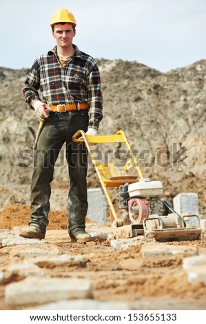 builder worker at outdoor sand ground compaction with vibration plate compactor machine before concrete filling