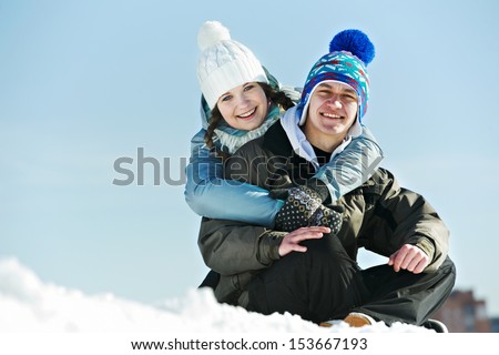 Smiling young couple in warm clothing on snow at winter outdoors