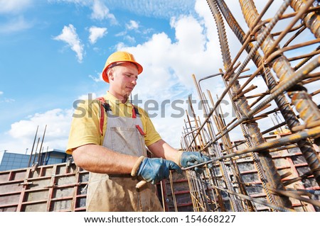 builder worker knitting metal rods bars into framework reinforcement for concrete pouring at construction site
