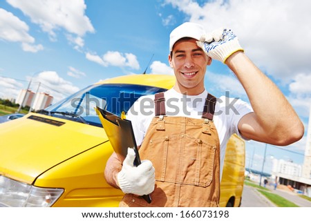Smiling young male delivery courier man in front of cargo van for delivering or relocation