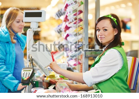 Customer buying food at supermarket and making check out with cashdesk worker in store