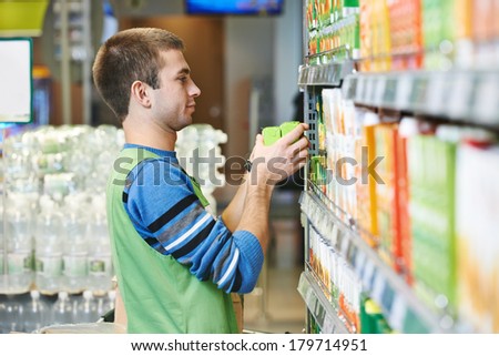 Merchandising. Sales assistant in supermarket lay out goods on supermarket shelves at store