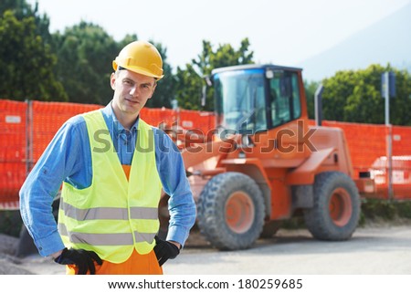 construction worker in safety protective work wear at construction site in front of loader machinery