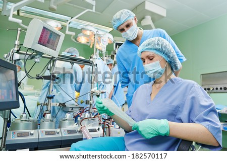 Surgery assistant nurse working with artificial cardiac valve at operation in cardiology clinic
