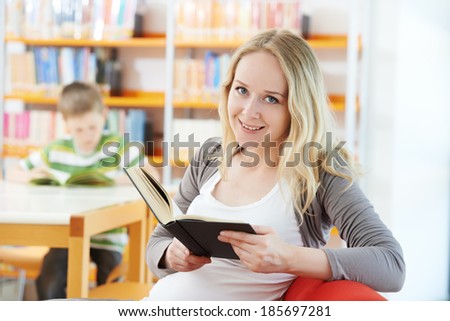Young smiling woman in a library with book at self-education