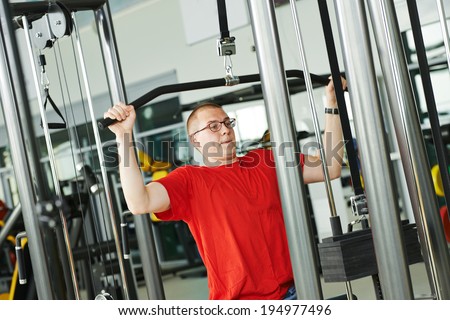 fitness man doing back muscles exercises with training weight machine station in gym