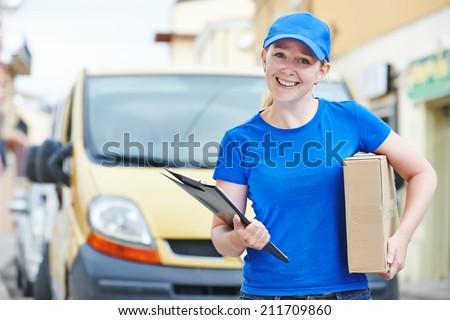 Smiling female postal delivery courier woman outdoors  in front of cargo van delivering package
