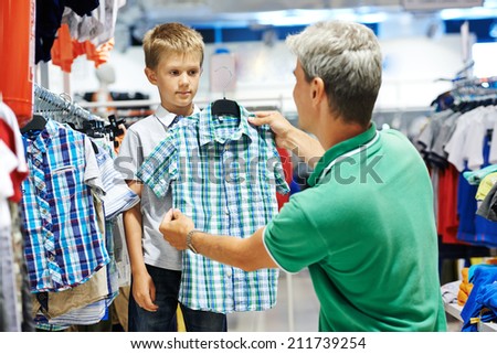 man father choosing shirt with son boy during shopping at garments shop