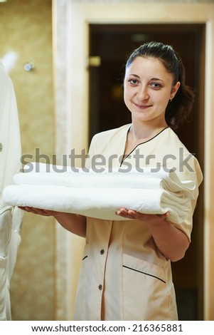 Hotel room service. female housekeeping worker with bedclothes linen in cart
