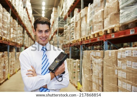 smiling manager in warehouse with bar code scanner