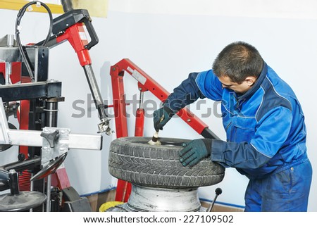 Auto repairman lubricating automobile car wheel during tyre fitting or tire replacing