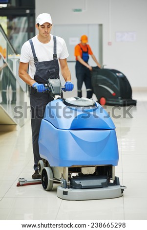 Cleaner male man workers with mop in uniform cleaning corridor pass or hall floor of business building