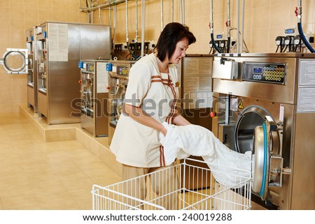 cleaning services. Woman loading laundry washing machine with cloth