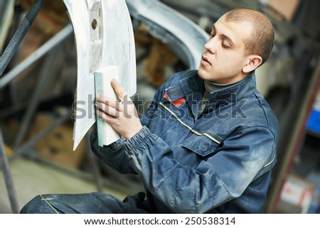 auto mechanic worker sanding polishing bumper car at automobile repair and renew service station shop by sandpaper