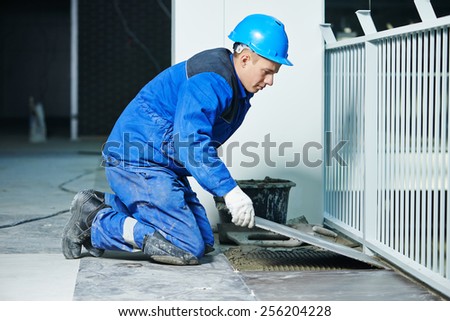 industrial tiler builder worker installing floor tile at repair renovation work