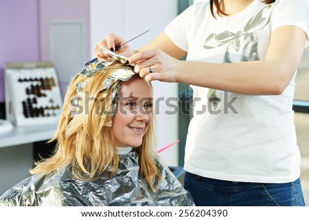 Highlight. Hairdresser woman making highlighting coloring of female client hair in beauty parlour hairdressing salon