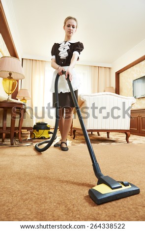 Hotel service. female housekeeping worker with vacuum cleaner in room apartment
