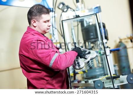 glazier worker with suction cup holding glass at double glazing window manufacture