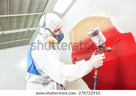 auto painting worker. red car in a paint chamber during repair work