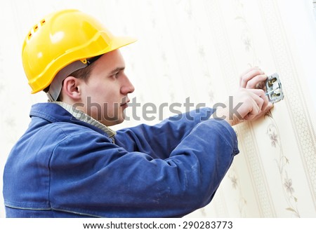 electrician worker installing and light switch or power wall outlet socket