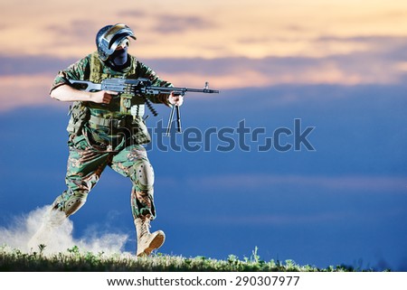 military. soldier in uniform running with machine gun weapon on sunset during attack outdoors. Authentic shooting in challenging conditions. Maybe little blurred.