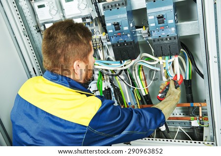 adult electrician builder engineer making electrical measure with equipment in fuseboard