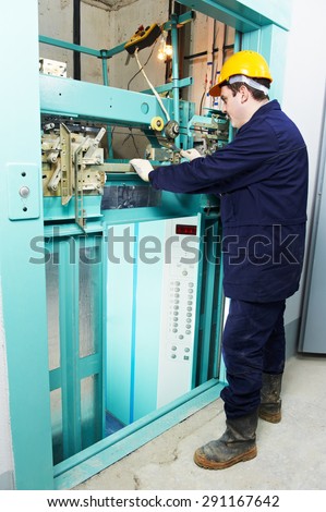 male technician machinist worker adjusting elevator mechanism of lift with spanner