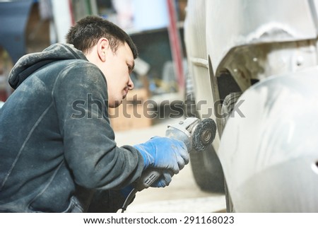 auto mechanic worker sanding polishing bumper car at automobile repair and renew service station shop by polishing grinding machine