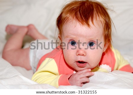 little baby in prone position with wide opened eyes