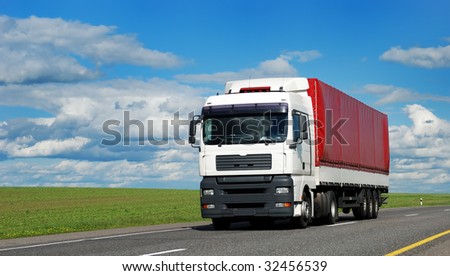 white lorry with red trailer on the highway over blue cloudy sky