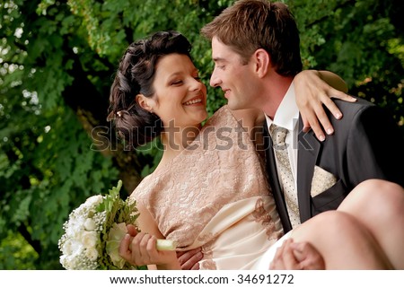 Happy smiling wedding couple outdoors. Man is holding woman with bunch of flowers in his arms. Find other nice peoples photos in my portfolio.