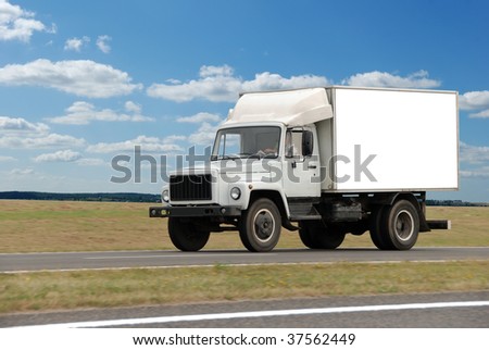single white middle truck moving on highway over blue cloudy sky